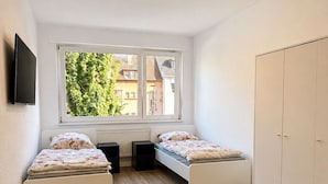 Ein Schlafzimmer mit zwei Betten, einem Fenster, einem Kleiderschrank und einer Deckenleuchte.