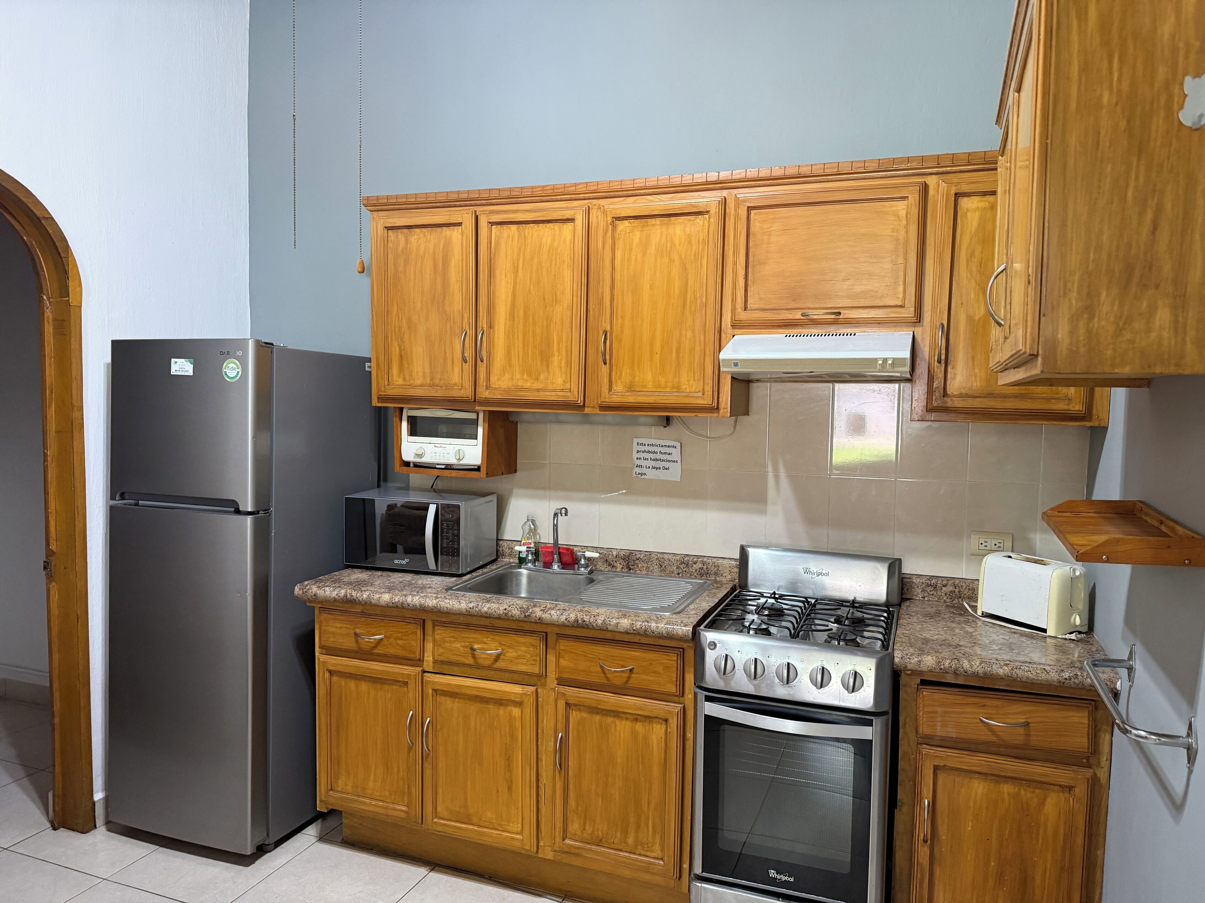 A kitchen with wooden cabinets, a stainless steel refrigerator, a microwave, a gas stove, and a built-in oven.