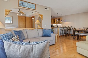 Ein Wohnzimmer mit einer Couch, ein Essbereich mit Stühlen, eine Küche mit Schränken und einem Deckenventilator.
