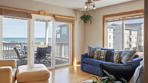 A living room with a blue sofa, beige armchair, and a wooden floor. - Ocean & Lake View |3BR |Steps to Beach & Boardwalk (Carolina Beach)