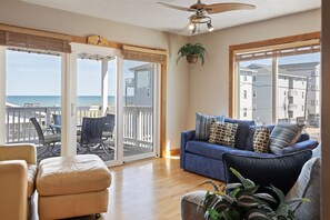 Ein Wohnzimmer mit blauem Sofa, beigem Sessel und Holzboden.