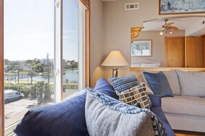 Ein Zimmer mit großem Fenster, einer Couch, einer Lampe und einem Deckenventilator.