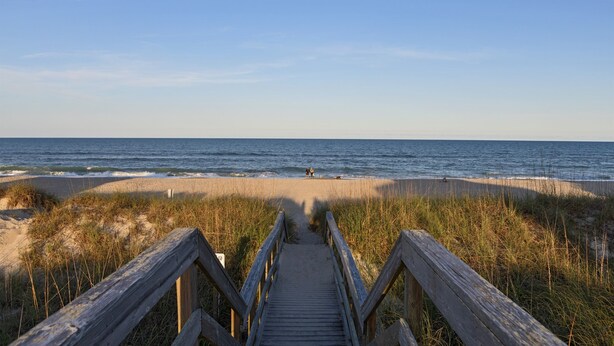 A wooden boardwalk leading to a beach with sand dunes and grass. - Ocean & Lake View |3BR |Steps to Beach & Boardwalk (Carolina Beach)
