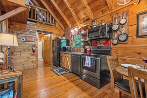 Ein Holzblockhaus-Innenraum mit Küche, Essbereich und Schlafzimmer im Heuboden.