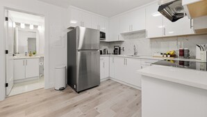 Une cuisine moderne avec des armoires blanches, un réfrigérateur en acier inoxydable et un four à micro-ondes.