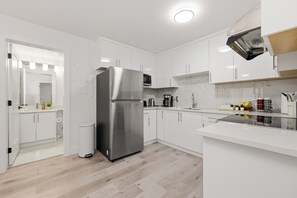 Eine moderne Küche mit weißen Schränken, einem Edelstahlkühlschrank und einer Mikrowelle.