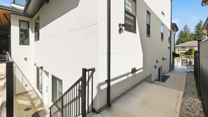 Un bâtiment blanc avec un escalier, une rambarde noire et une petite fenêtre.