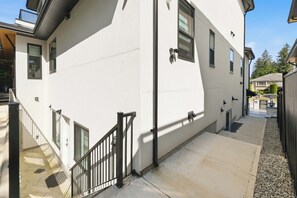 Ein weißes Gebäude mit einer Treppe, einem schwarzen Geländer und einem kleinen Fenster.