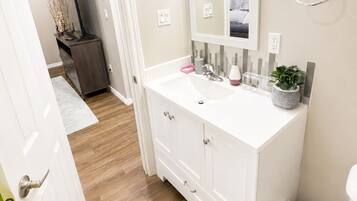 A bathroom with a white vanity, a mirror, a towel ring, and a potted plant.