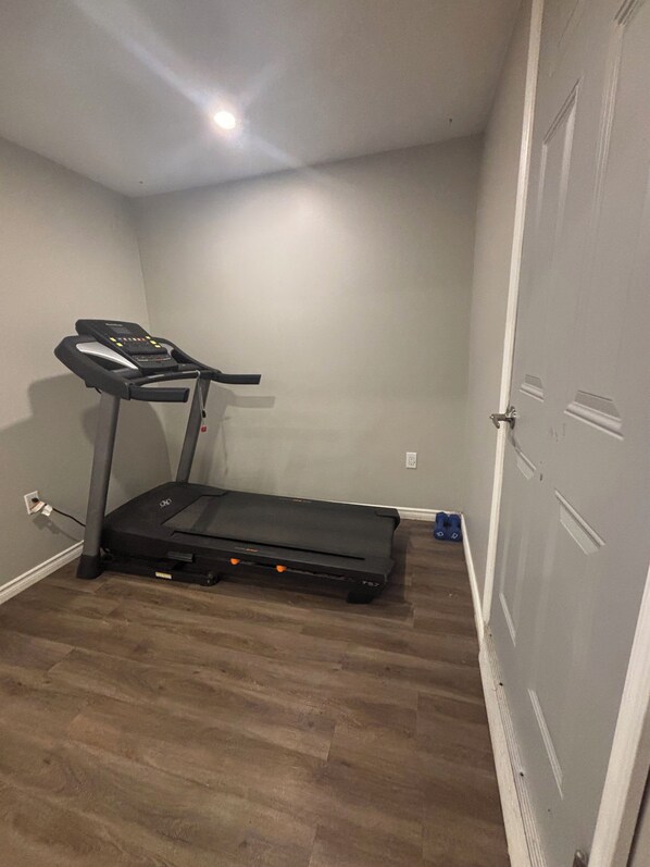 Una habitación con una cinta de correr, una puerta y un enchufe.