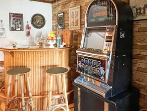 Zona de bar con una máquina tragamonedas que dice 'BONUS POKER' y un mostrador con taburetes.