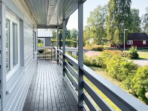 A covered wooden deck with a railing, a grill, and a table. - 7 Person Holiday Home in Monsteras (Monsteras)