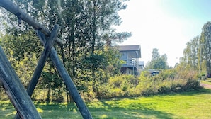 Un espacio cubierto de césped con una estructura de madera y un edificio al fondo.