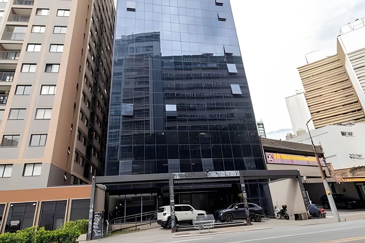 Un edificio moderno con facciata in vetro, un'area parcheggio con auto e un negozio ben visibile.