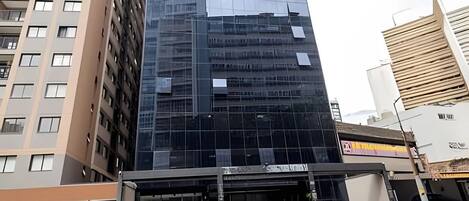 Un edificio moderno con facciata in vetro, un'area parcheggio con auto e un negozio ben visibile.