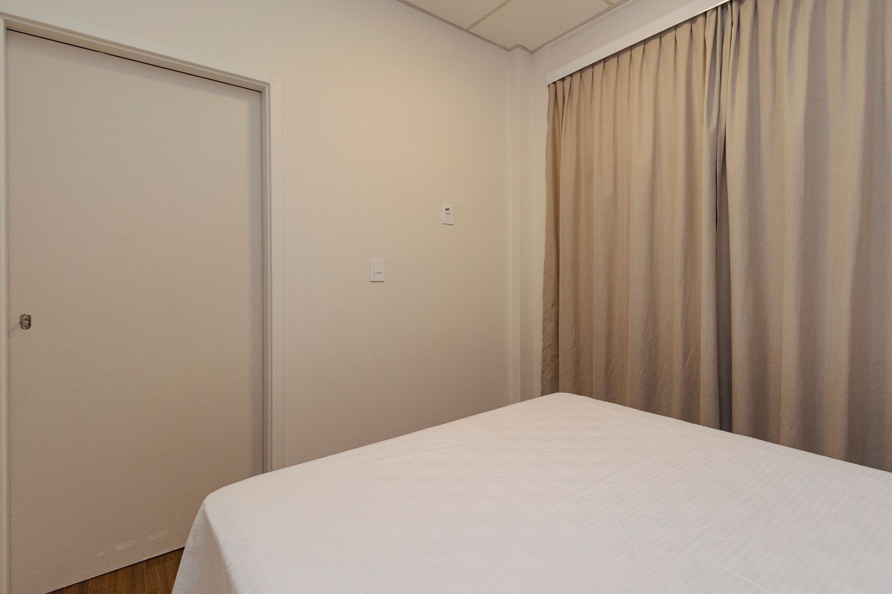 A room with a bed, a door, and a curtain.