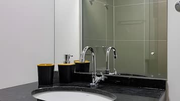 A modern bathroom with a large mirror, two sinks, and a shower.