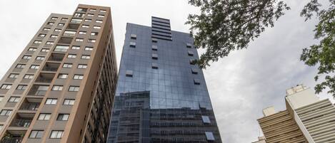 A modern high-rise building with multiple floors, large windows, and a reflective glass facade.