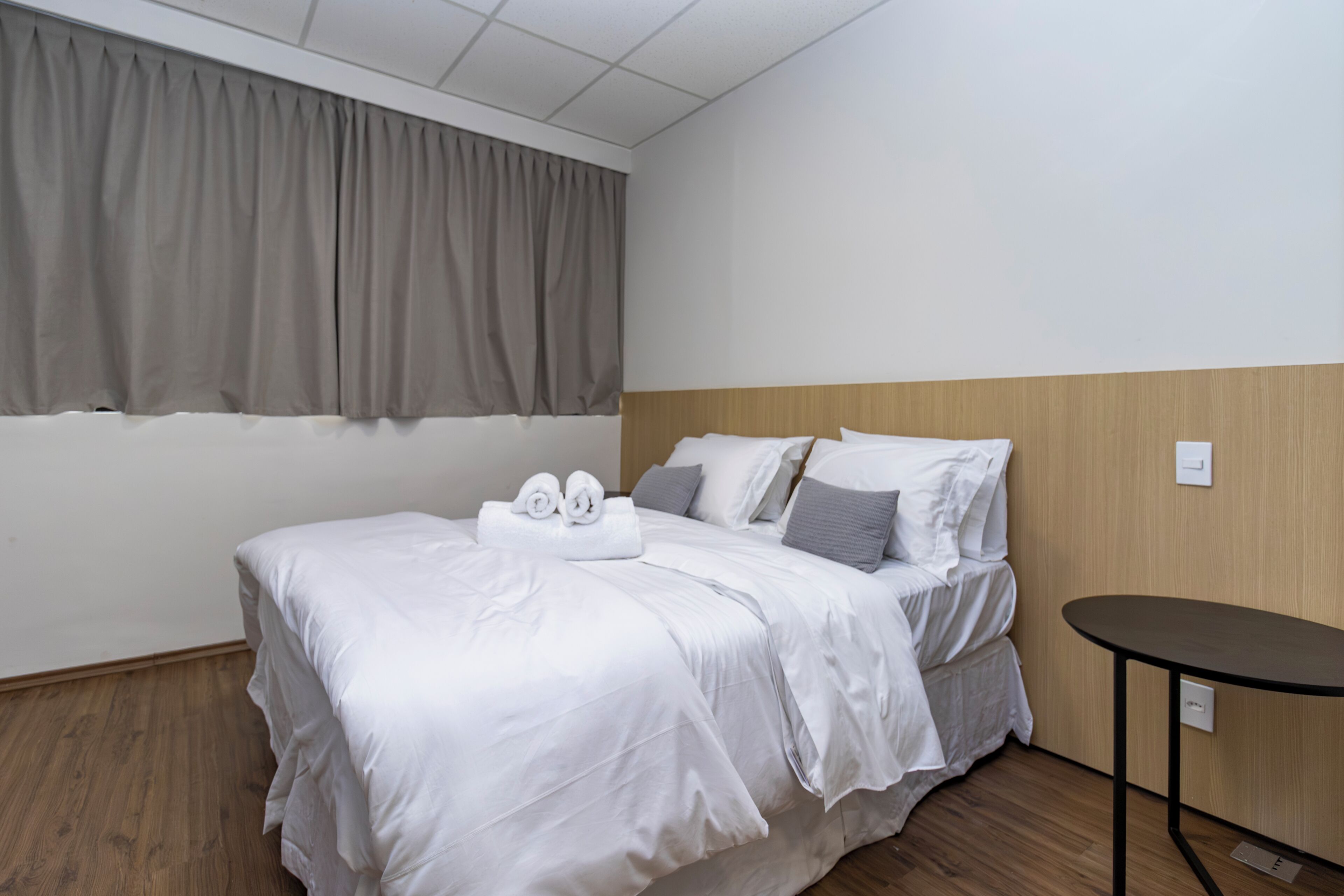 Una habitación de hotel con una cama, una mesita y una ventana con cortinas.
