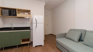 Eine kleine Küche mit Mikrowelle, Kühlschrank und grünen Schränken.