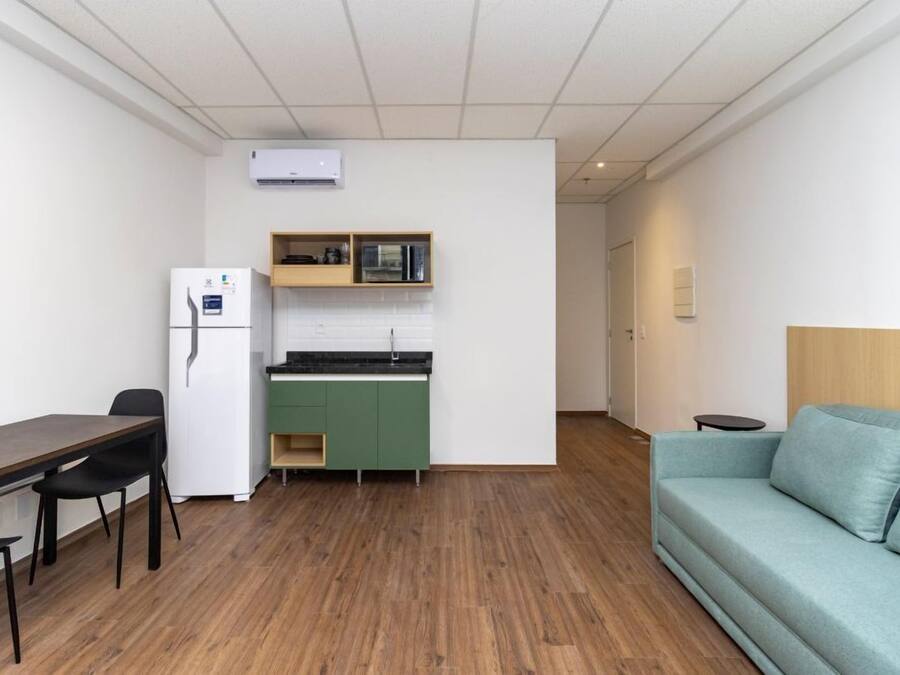 Un espacio habitable compacto con kitchenette, una mesa de comedor con sillas, un sofá y una pequeña mesita auxiliar.