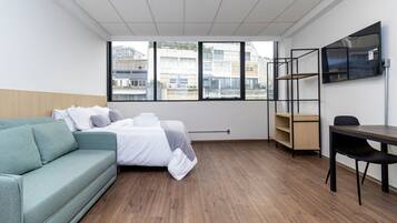 Habitación de hotel con cama, sofá, escritorio y televisor.