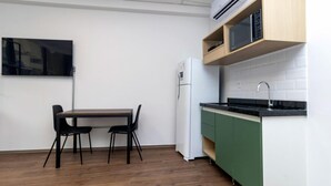 A compact kitchen with a microwave, a refrigerator, a dining table with chairs, and a TV mounted on the wall. - Belong Stay Martins Fontes by Unna (São Paulo)