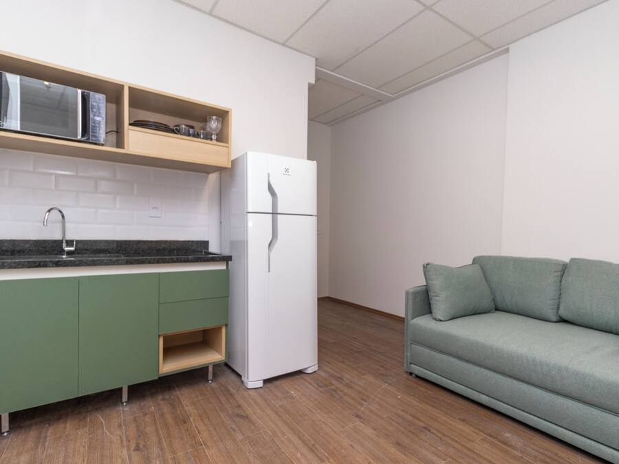 A kitchenette with a microwave, refrigerator, and green cabinets.
