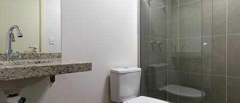 A bathroom with a shower, toilet, sink, and a mirror.