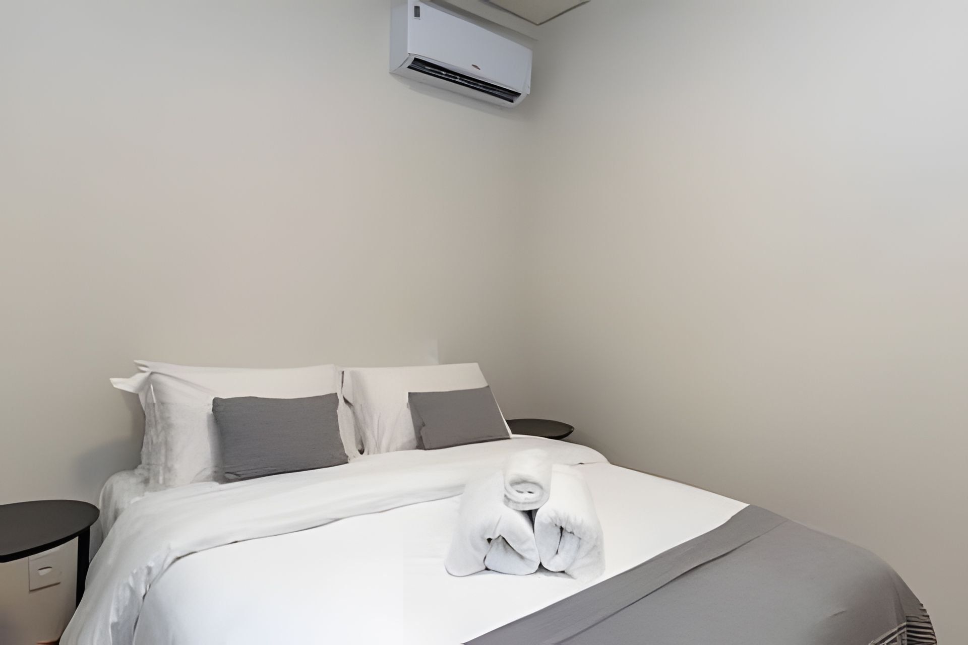 Une chambre d’hôtel équipée d’un lit, d’oreillers, d’une table de chevet et d’un appareil de climatisation.