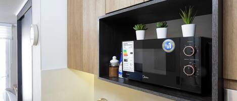 A kitchen with a built-in microwave, a sink, and a cabinet with potted plants.
