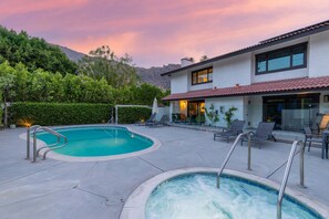 Ein modernes Haus mit Swimmingpool und Whirlpool, umgeben von viel Grün mit Blick auf das Gebirge.