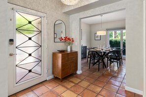 Eine Küche mit Essbereich, einem Holzkabinett, einem Spiegel und einer Tür mit geometrischem Glasdekor.