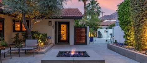 Une maison moderne dotée d’un foyer extérieur, d’un espace salon de jardin et d’un jardin bien entretenu.