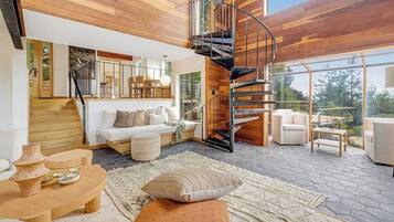 A modern interior with a spiral staircase, wooden flooring, and a seating area with cushions.