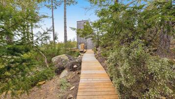 A wooden pathway leading to a stone building surrounded by dense forest.