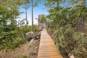 A wooden pathway leading to a stone building surrounded by dense forest. - Ocean-view main house and private cottage (Gualala)