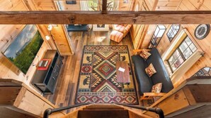 A wooden cabin interior with a central rug, seating area, and a view of the outdoors. - Cozy Mountain Retreat w/ Hot Tub, Fire Pit & Views (Sevierville)
