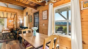 A wooden interior with a dining table, chairs, a sofa, and a chandelier. - Cozy Mountain Retreat w/ Hot Tub, Fire Pit & Views (Sevierville)