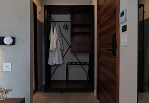 A walk-in closet with a wooden door, a hanging rack, and a shelf unit.