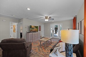 A living room with a ceiling fan, a sofa, a coffee table, and a lamp.