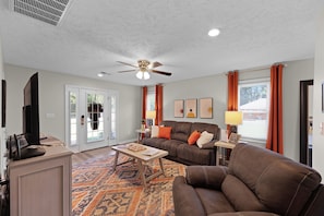 A living room with a ceiling fan, a sofa, a coffee table, and a television.