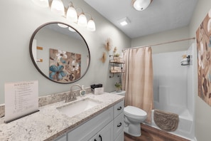 A bathroom with a marble sink, a toilet, a shower, and a large mirror.