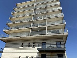 Ein mehrstöckiges Gebäude mit Balkonen, großen Fenstern und einer glatten Fassade.