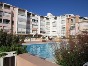 Ein Wohnkomplex mit Schwimmbad, Balkonen und blauem Himmel.