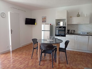 Eine kompakte Küche mit Esstisch, Stühlen, Fernseher und Mikrowelle.