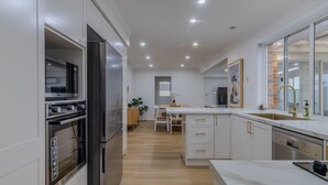Eine moderne Küche mit Einbaugeräten, einem Essbereich und einem großen Fenster.