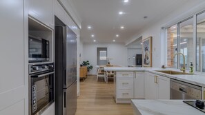 Une cuisine moderne dotée d’appareils électroménagers intégrés, d’un coin repas et d’une grande fenêtre.