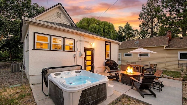 Een huis met een jacuzzi, buiten zitplaatsen en een vuurkorf.