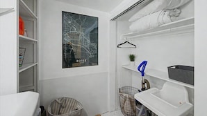 Een compacte, moderne badkamer met een kaart, witte planken, een ophangrek en een kleine plant.